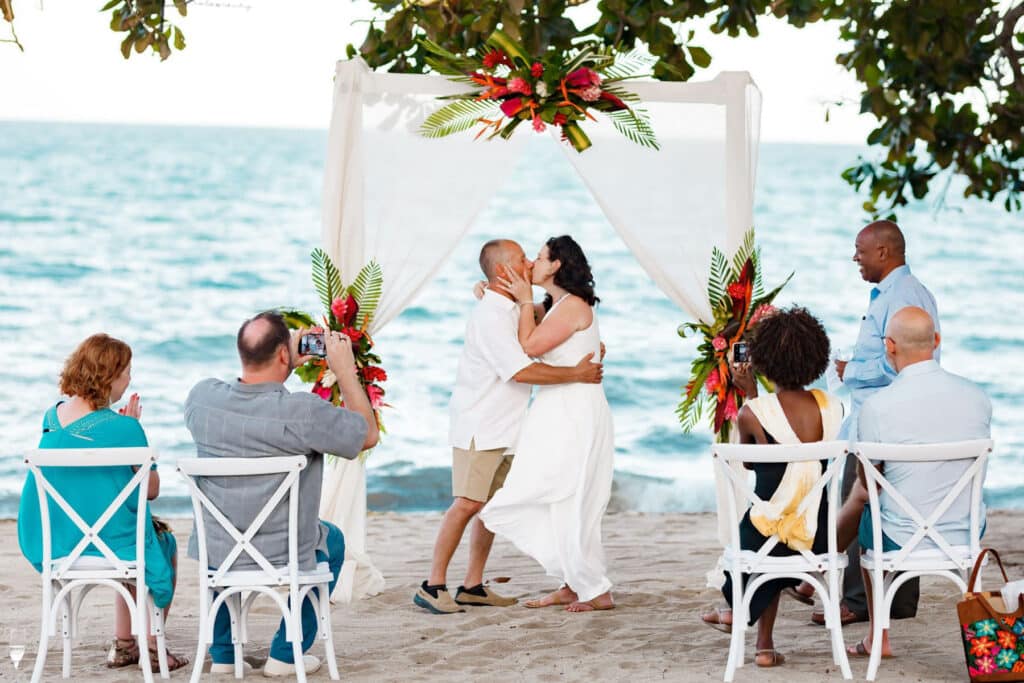 A newly wedded couple kissing on the beach