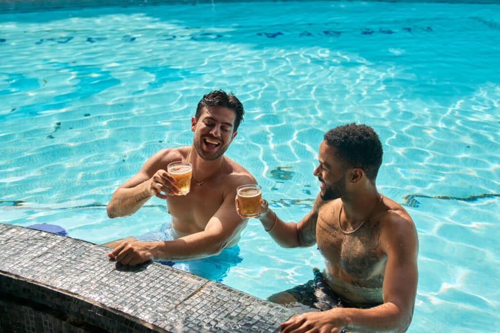 Deux amis se détendant avec des boissons dans la piscine au bar immergé de l’Umaya Resort, Maya Beach, péninsule de Placencia, Belize