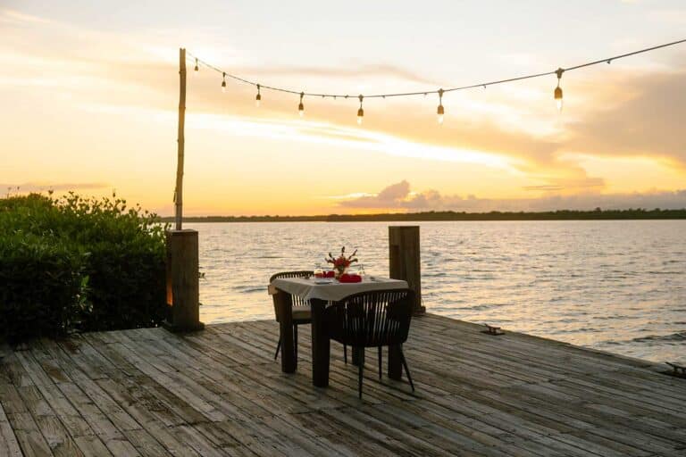 Romantically arranged private dinner table beside the tranquil lagoon at Umaya Resort, Maya Beach, Placencia Peninsula, Belize